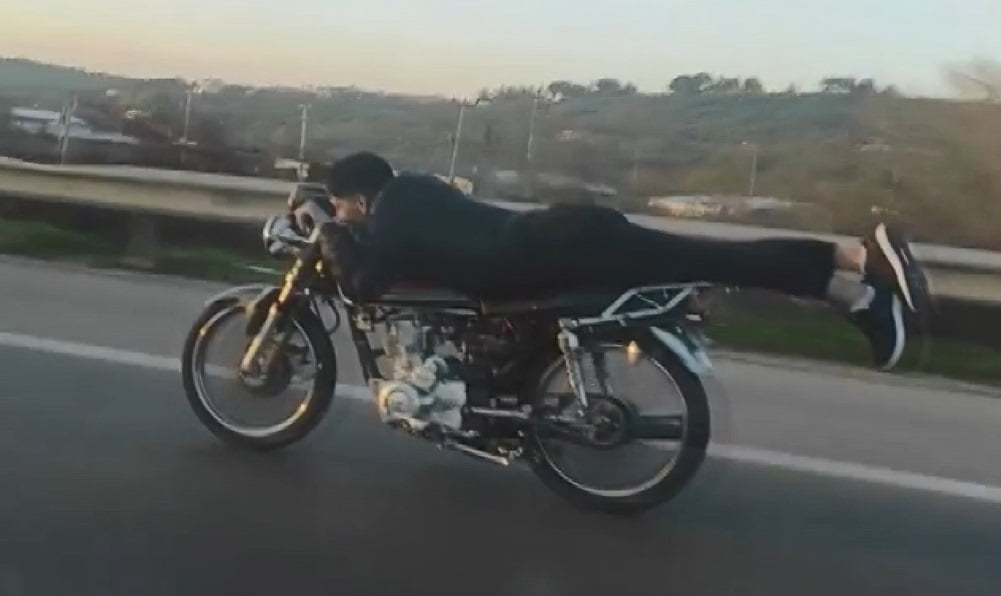 Kasksız sürücü motosikleti yatarak kullandı